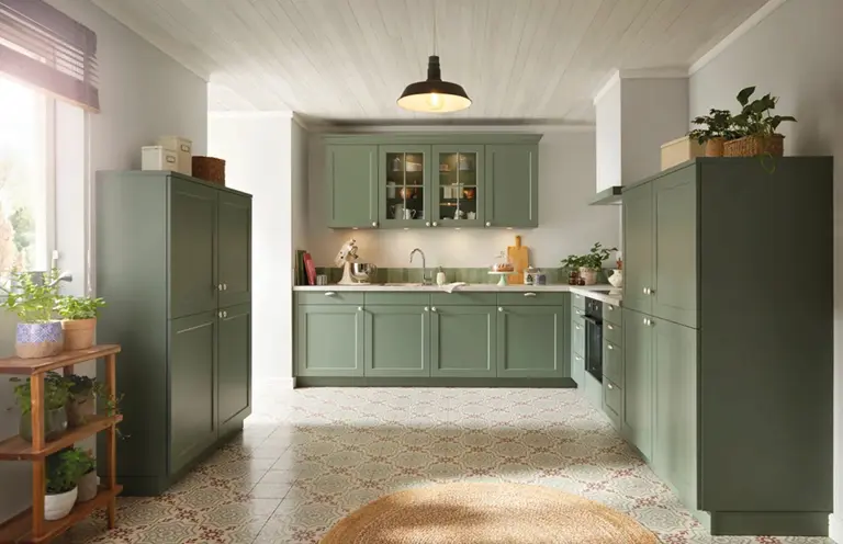 Grüne Landhausküche mit Fronten in Mattoptik, offener Gestaltung, Hängeschränken mit Glaseinsätzen und gemustertem Boden – ideal für kleine Küchen mit viel Stauraum und natürlichem Wohngefühl.